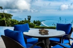 Outdoor dining with ocean view, lush greenery, and cloudy sky in Costa Rica.