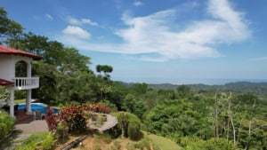 Scenic view of ocean and mountains from a Costa Rican home with lush greenery.