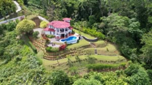 Aerial view of a Spanish Colonial-style home with pool and ocean view in Dominical.