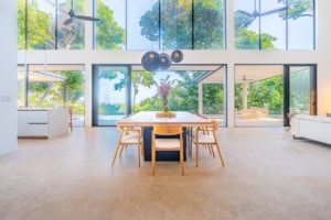 Spacious dining area with large windows overlooking lush greenery and ocean.