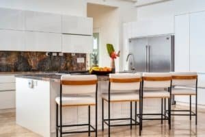 Contemporary kitchen with white cabinets, granite countertops, and bar stools.