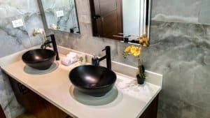 Modern bathroom with two black vessel sinks and marble walls in Dominical.