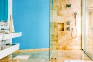 Modern bathroom with blue wall, glass shower, and ocean view in Costa Rica.