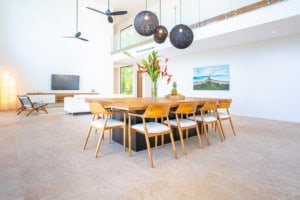 Spacious dining area with wooden table, tropical plants, and modern decor.