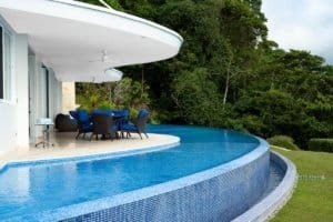 Infinity pool with outdoor dining area overlooking lush jungle in Dominical.