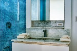 Contemporary bathroom with marble vanity and blue mosaic tiles.