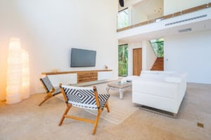 Bright, spacious living room with white sofa, wooden accents, and large windows.