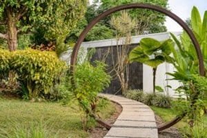 Lush garden with a circular metal arch and a stone pathway in Dominical.