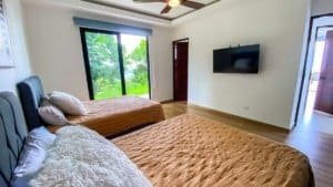 Spacious bedroom with mountain view, modern decor, and flat-screen TV.