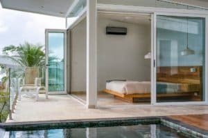Contemporary bedroom with glass walls overlooking pool and balcony in Costa Rica.