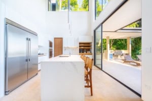 Bright modern kitchen with large sliding glass doors to outdoor patio and greenery.