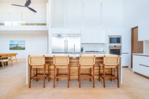 Contemporary kitchen with white cabinets, stainless steel appliances, and wooden bar stools.