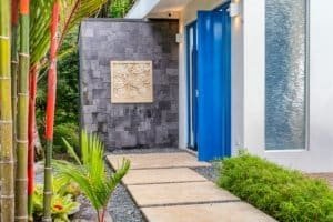 Contemporary entrance with blue door and lush tropical plants in Dominical.