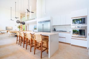 Bright, modern kitchen with white cabinets, island, and stainless steel appliances.