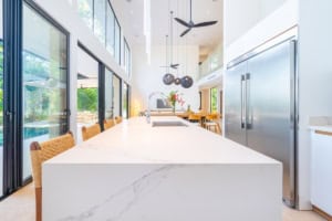 Bright, modern kitchen with large island, stainless appliances, and ocean view.