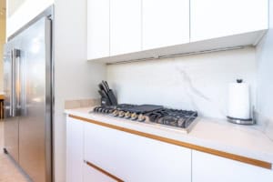 Contemporary kitchen with gas stove, white cabinets, and marble backsplash.