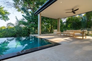Modern tropical home with infinity pool and lush jungle surroundings.