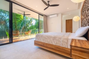 Modern bedroom with ocean view balcony, tropical surroundings, and stylish decor.