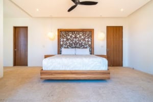 Modern bedroom with wooden accents, ceiling fan, and minimalist decor.