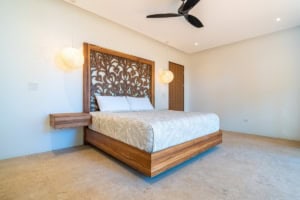 Modern bedroom with wooden headboard, white bedding, and ocean view.