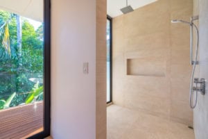 Modern bathroom with large windows overlooking lush greenery in Costa Rica.