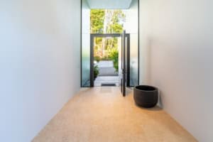 Minimalist entry hall with open door to lush outdoor scenery.