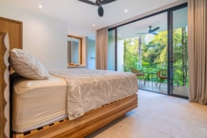 Spacious bedroom with balcony overlooking lush green forest in Dominical, Costa Rica.