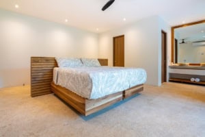 Spacious bedroom with wooden bed and neutral decor in tropical home.