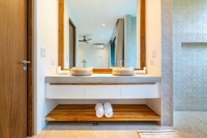 Modern bathroom with double sinks, wooden shelf, and textured wall in Dominical.