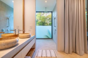 Modern bathroom with double sinks and ocean view through large window.