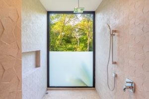 Bright bathroom with large window overlooking lush green trees in Costa Rica.