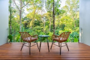 Balcony with two chairs and a table overlooking lush tropical forest.