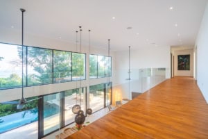 Modern interior with large windows overlooking lush greenery and pool.