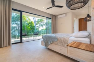 Modern bedroom with large glass doors overlooking lush tropical landscape in Dominical.