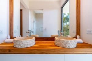 Modern bathroom with double stone sinks and large window overlooking nature.