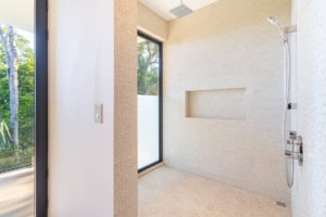Bright tropical bathroom with shower, large window, and textured walls.