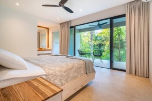 Spacious bedroom with balcony overlooking lush tropical landscape in Dominical.
