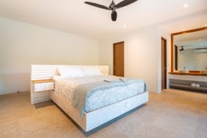 Modern bedroom with king bed, minimalist decor, and tropical style.
