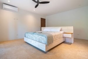 Spacious bedroom with a large bed, ceiling fan, and ocean view in Dominical.