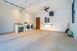 Bright laundry room with washer, dryer, ceiling fan, and large window.