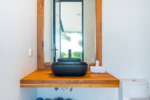 Contemporary bathroom with black vessel sink and wooden vanity.