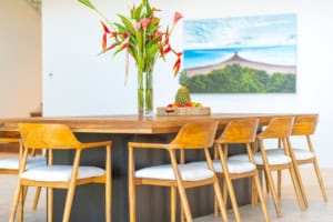 Contemporary dining area with wooden table, chairs, and tropical artwork.