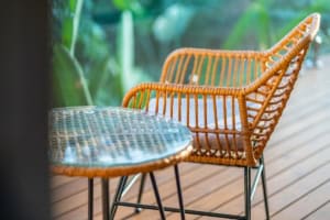 Wicker chair and table on wooden deck with lush greenery in Dominical.