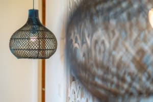 Close-up of a decorative hanging lamp and textured wall in a tropical home.