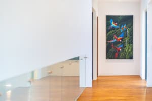 Contemporary interior with wooden flooring and colorful bird painting on the wall.