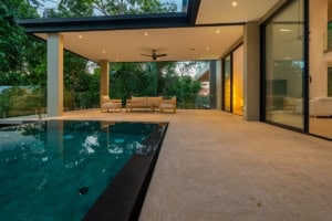 Luxury tropical home with pool, outdoor seating, and lush garden view.