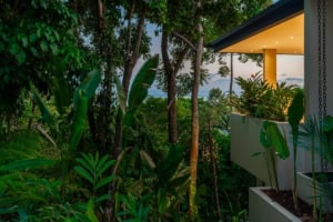 Modern tropical home with ocean view, lush greenery, and outdoor balcony.