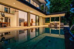 Modern tropical home with infinity pool, outdoor lounge, and lush surroundings.