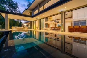 Modern tropical home with infinity pool, open living space, and ocean view.