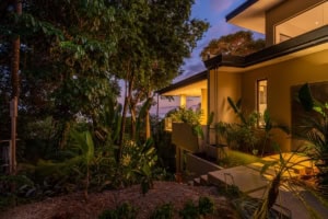 Modern Costa Rican home with lush garden and ocean view at sunset.